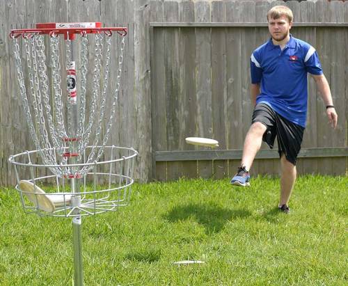 C.J. starts a disc towards the basket in an unconventional manner.