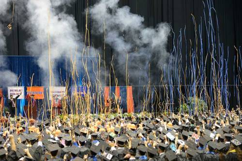 The smoke from indoor fireworks and streamers rain down on the graduates.